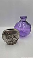 Front view of pewter vase and purple glass vase