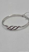 Full view of silver-tone bangle showing twisted crystal design