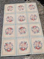 Full view of rectangular hooked rug showing twelve floral square panels and borders