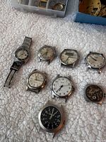 Overview of nine watch heads including one with band on textured surface