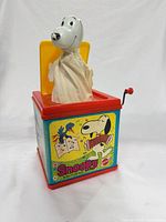 Jack-in-the-box open with Snoopy figure popped up, front panel graphic visible