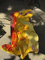 Deflated yellow and orange dinosaur inflatable pool toy laid out on surface