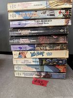 Stack of ten paperback romance novels showing spines with titles and authors