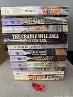 Stack of 11 paperback books, spines showing titles and authors