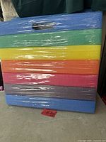 Shrink-wrapped stack showing multi-colour foam knee pads and handle slot