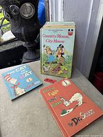 Three hardcover children’s books displayed: Country Mouse, City Mouse, The Cat in the Hat, Green Eggs and Ham