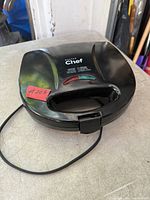 Closed appliance showing brand name, indicator lights, handle and power cord
