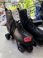 Front view of both black quad skates showing laces, toe caps, wheels