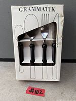 Front of sealed Grammatik cutlery set box showing utensils and black handles