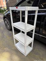 Full view of white plastic 4-shelf unit standing outdoors