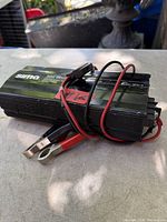 Overall view of Sima 300W power inverter with attached battery clamp leads