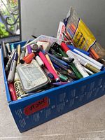 Top view of box showing mixed pens, pencils, coloured pencils pack, stapler, accessories
