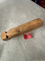 Overall view of wooden train whistle showing engraving and size reference tag