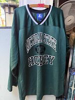 Full front view of green Michigan State Hockey jersey on hanger
