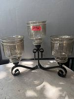 front view of iron candle holder with three glass shades attached