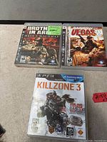 Front view showing all three PS3 game cases: Killzone 3, Brothers in Arms: Hell's Highway, Rainbow Six Vegas 2