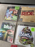 Four PS3 game cases laid out: Carnival Island, Tony Hawk: Ride, Blur, The Sims 3 Pets