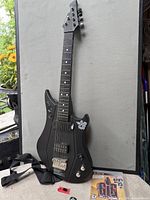 Full view of guitar controller with strap; PS3 game case at base