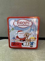Front of square red Rudolph tin with holiday illustration