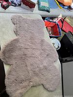Full view of the light grey bear-shaped plush rug on a table surface
