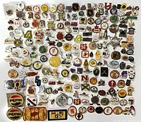 Wide view of entire assortment of enamel pins laid out on white surface