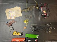 Overview of rolling stock, track, accessories, manuals and power pack on black surface