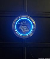 Clock illuminated on wall showing blue neon ring and #15 face
