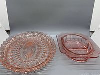 Both pink pressed glass serving pieces side by side
