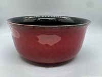 Side view of red stoneware bowl showing red exterior and black interior