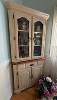 Full view of corner china cabinet showing upper glass doors and lower storage