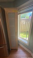 Cabinet front beside refrigerator showing light wood finish and translucent door insert