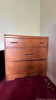 Front view of three-drawer oak-tone dresser