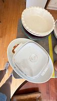 Top view of stacked pie dishes, platter, CorningWare casserole with plastic lid