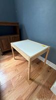 Full view of side table showing white top and natural wood legs