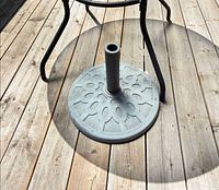 Top view of round decorative metal umbrella base on wooden deck