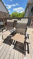 Four beige sling patio chairs on deck
