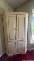 Full front view of corner armoire showing double doors and angled base