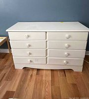 Front view of white six-drawer dresser showing layout and knobs