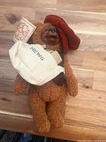 Front view of teddy bear showing hat, vest, satchel, tag and overall condition