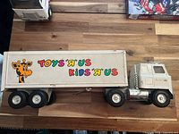 Left side view of white die-cast semi truck and trailer showing Toys "R" Us / Kids "R" Us decals and giraffe graphic