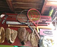 Lot overview showing gloves, bats, racquets, golf clubs and golf balls