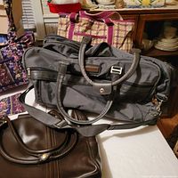 Group of bags showing carry-on, tote, quilted purse set, briefcase
