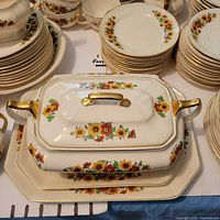 Overhead view of covered casserole, stack of plates, bowls showing floral pattern and gold trim
