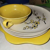 Stack showing yellow Italian cake plate at bottom, dogwood plates, condiment bowl