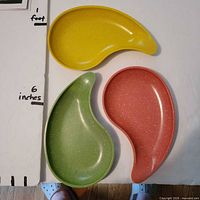 Top view of yellow, green and pink kidney-shaped plates showing colors and shape
