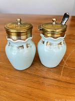 Front view of both porcelain vessels with brass lids