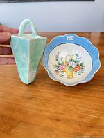 Front view of both items: floral bowl and celadon wall pocket