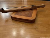 Wooden bread slicer resting on patterned wooden board