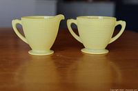 Front view of pastel yellow Saguenay creamer and sugar bowl showing woven grid texture and handles