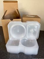 stack of clear plastic snack containers with two cardboard boxes behind
